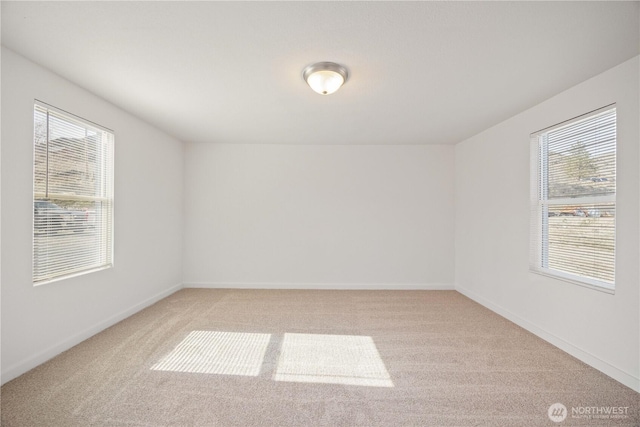 unfurnished room with baseboards, plenty of natural light, and light carpet