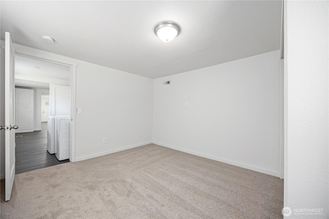 spare room featuring visible vents, baseboards, washing machine and dryer, and carpet flooring