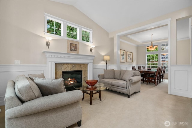 living area featuring a wealth of natural light, light colored carpet, and wainscoting