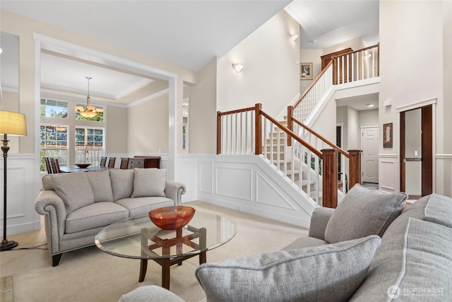 living room with a wainscoted wall, light carpet, stairs, and a decorative wall