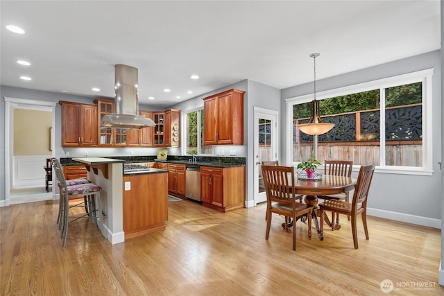 kitchen featuring stainless steel dishwasher, light wood-style flooring, brown cabinetry, and island range hood