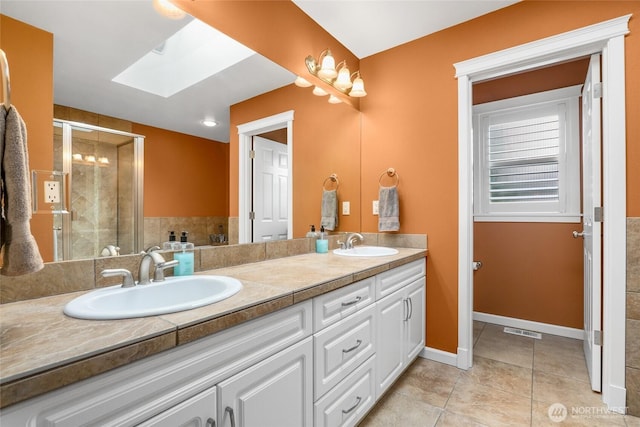 full bathroom featuring tile patterned flooring, a stall shower, double vanity, and a sink