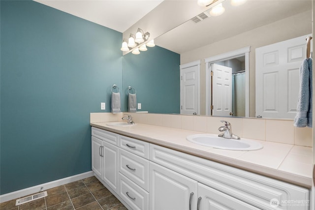 bathroom with double vanity, visible vents, and a sink