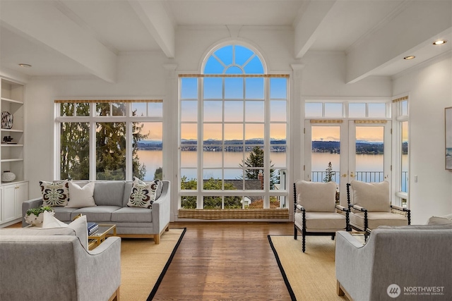 living room featuring beamed ceiling, french doors, a water view, and wood finished floors