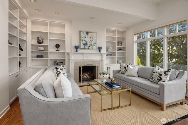 living area featuring built in shelves, ornamental molding, wood finished floors, a high end fireplace, and recessed lighting