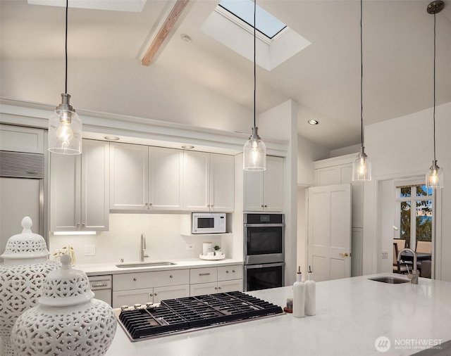 kitchen with light countertops, lofted ceiling with skylight, stainless steel appliances, and a sink