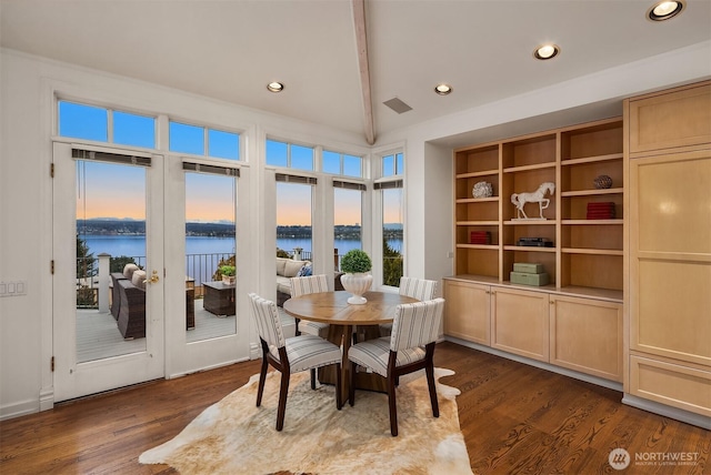 dining space with visible vents, a water view, and dark wood-style flooring