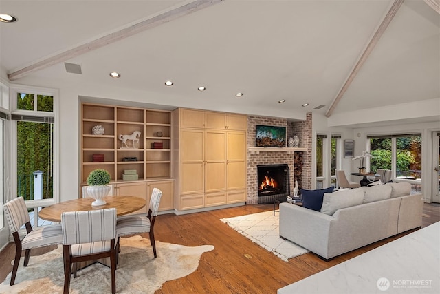 living area with light wood-type flooring, visible vents, lofted ceiling with beams, recessed lighting, and a brick fireplace