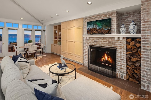 living area with recessed lighting, lofted ceiling, a brick fireplace, and wood finished floors