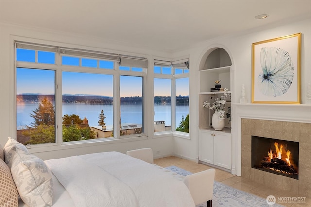 bedroom with a water view and a fireplace