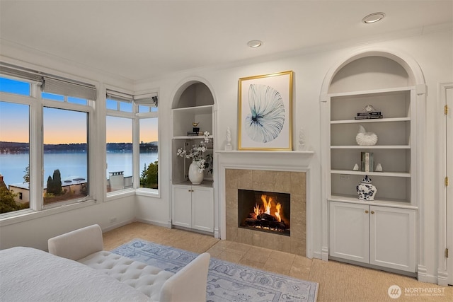 bedroom with a fireplace, crown molding, baseboards, and a water view