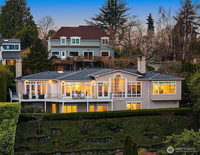 back of property featuring stucco siding, a balcony, and a chimney