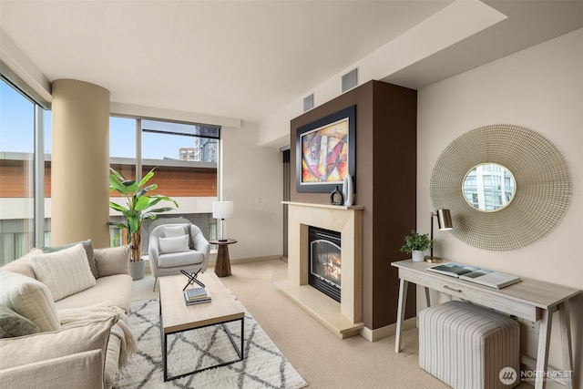 living area with a glass covered fireplace, light colored carpet, and baseboards