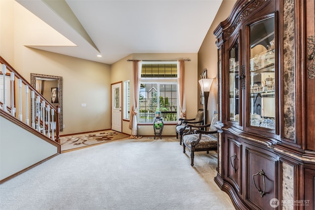 foyer entrance with baseboards, stairs, carpet, and vaulted ceiling