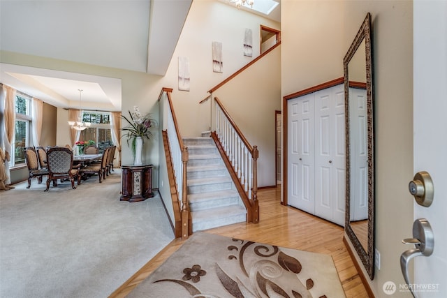 entrance foyer with stairs, an inviting chandelier, light wood finished floors, and light carpet