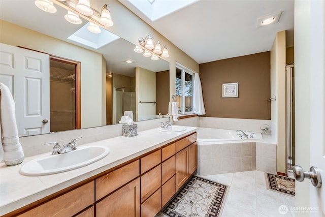 bathroom with a garden tub, a skylight, a stall shower, a sink, and tile patterned floors