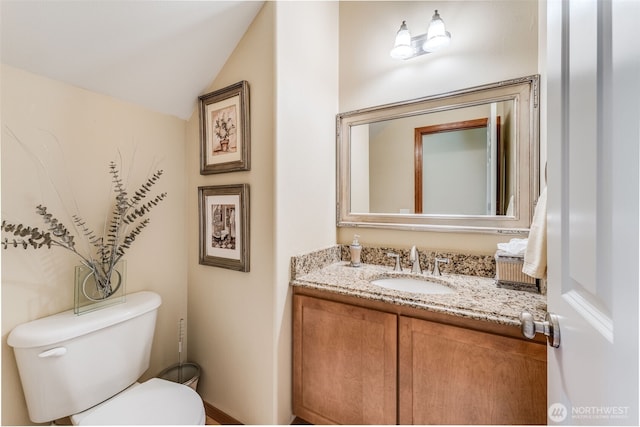 half bathroom with toilet, vanity, and vaulted ceiling