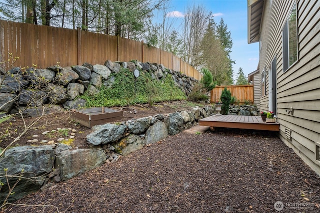 view of yard featuring a deck, a garden, and fence