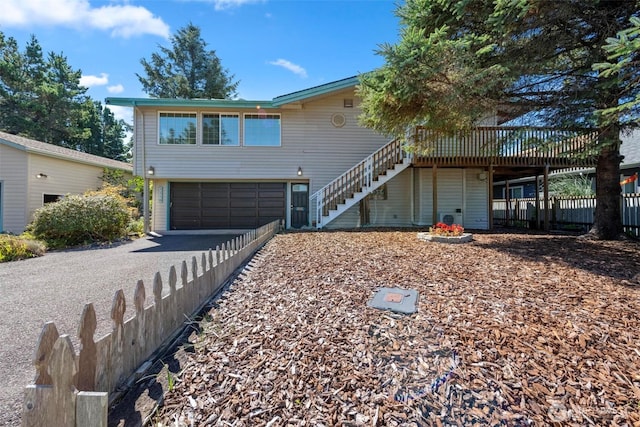 view of front of house featuring stairway, driveway, a garage, and fence