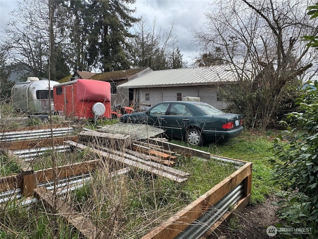 view of side of home featuring metal roof and a vegetable garden