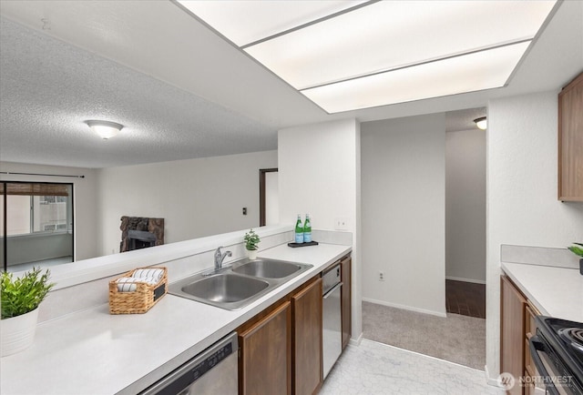 kitchen with a sink, a textured ceiling, dishwasher, and light countertops