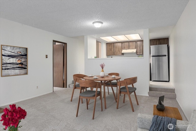 dining space with baseboards, light colored carpet, and a textured ceiling