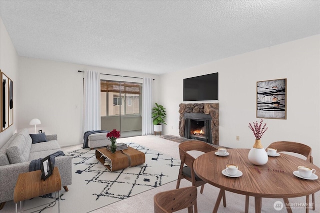 living area featuring a textured ceiling, a fireplace, and carpet flooring