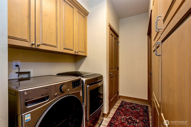 laundry area featuring washing machine and clothes dryer, baseboards, light wood-type flooring, and cabinet space