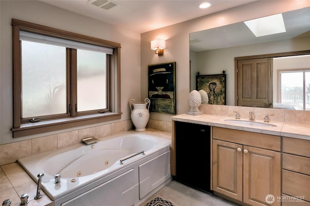 bathroom with visible vents, a skylight, vanity, and a tub with jets