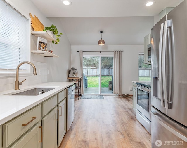 kitchen featuring tasteful backsplash, open shelves, a sink, light wood finished floors, and appliances with stainless steel finishes