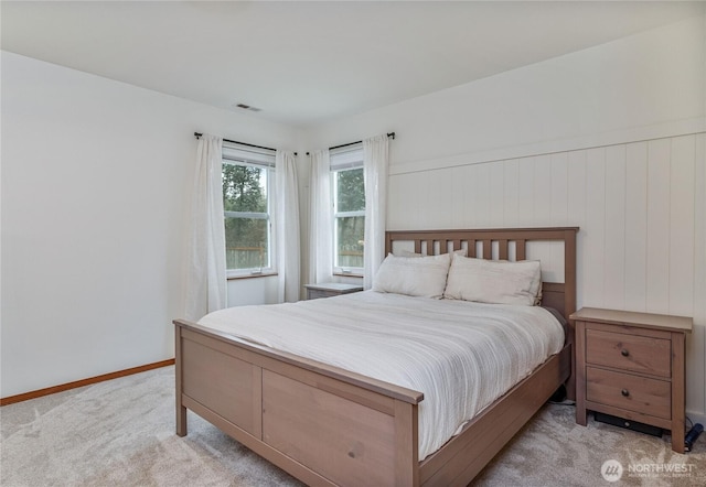 bedroom with wainscoting, baseboards, visible vents, and light colored carpet