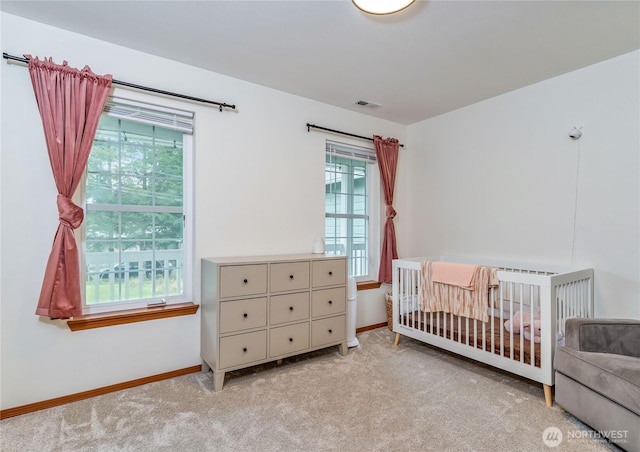 carpeted bedroom featuring a crib, baseboards, visible vents, and multiple windows