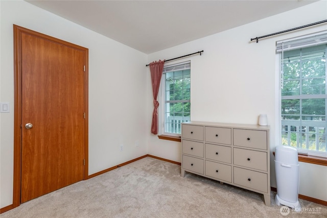 bedroom with baseboards, light colored carpet, and multiple windows