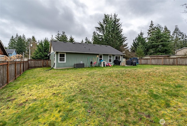 back of house featuring a fenced backyard, a yard, and central air condition unit