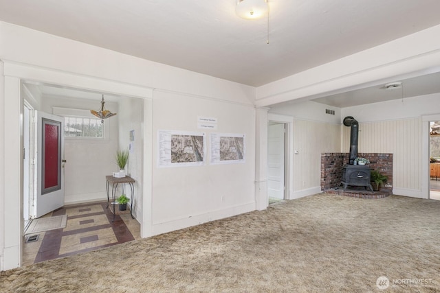 249 Cascade Ave, Langley, WA 98260 - unfurnished living room with a notable chandelier, visible vents, a wood stove, and carpet