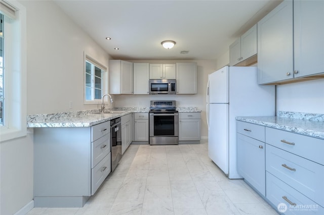 kitchen with light stone counters, gray cabinets, a sink, stainless steel appliances, and marble finish floor