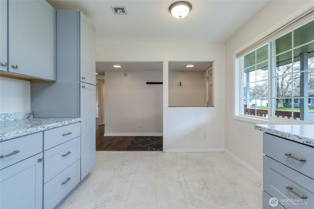 kitchen featuring light stone counters, visible vents, marble finish floor, and baseboards