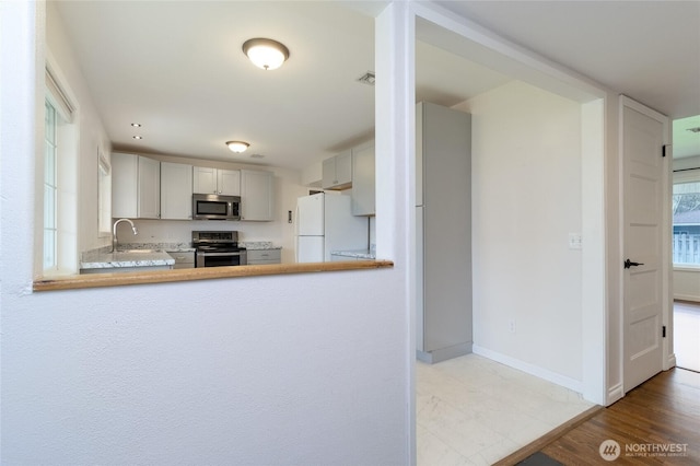 kitchen with visible vents, baseboards, a sink, stainless steel appliances, and light countertops