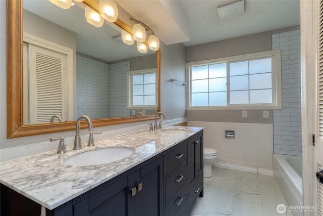 full bathroom featuring a sink, tile walls, toilet, and marble finish floor