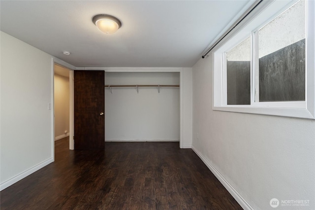 unfurnished bedroom with wood finished floors, a closet, and baseboards