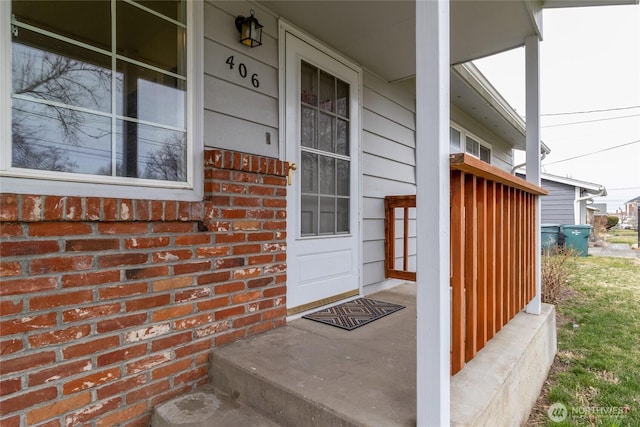 view of exterior entry featuring brick siding and a porch