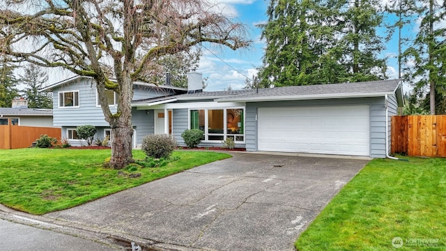 tri-level home featuring driveway, a front lawn, fence, an attached garage, and a chimney