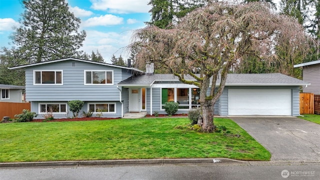 split level home featuring a front lawn, fence, a garage, and driveway