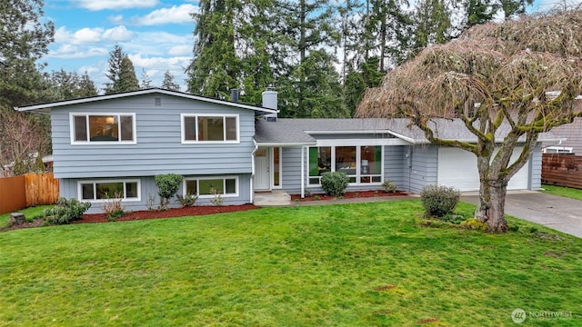 tri-level home with driveway, a chimney, a front lawn, and fence