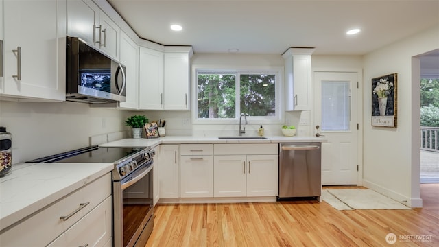 kitchen featuring a sink, white cabinetry, appliances with stainless steel finishes, and light wood finished floors