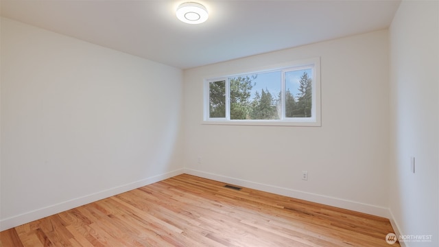 unfurnished room with visible vents, light wood-style flooring, and baseboards