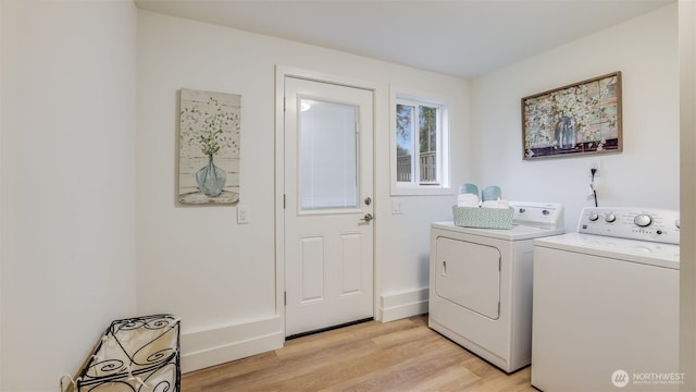 clothes washing area featuring laundry area, light wood-style flooring, separate washer and dryer, and baseboards