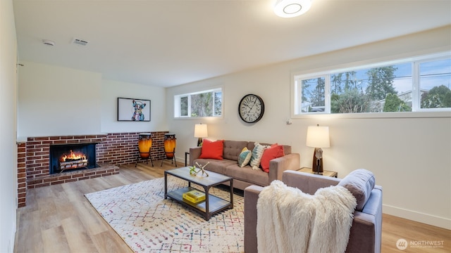 living room featuring visible vents, a fireplace, baseboards, and wood finished floors