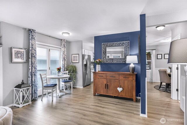 kitchen featuring light wood-style flooring, baseboards, and stainless steel refrigerator with ice dispenser