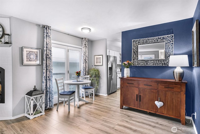 dining space with light wood-type flooring and baseboards